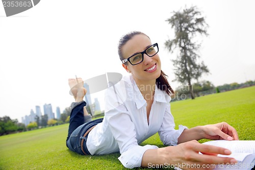 Image of Young woman reading a book in the park