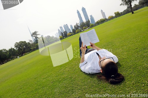 Image of Young woman reading a book in the park