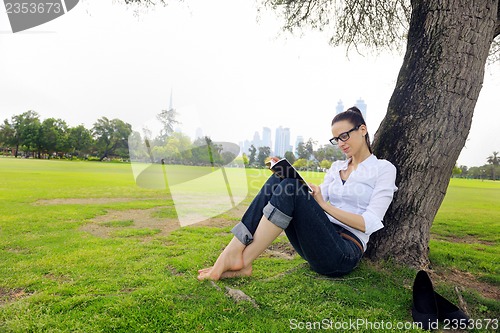 Image of Young woman reading a book in the park