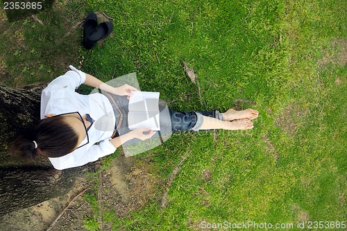 Image of Young woman reading a book in the park