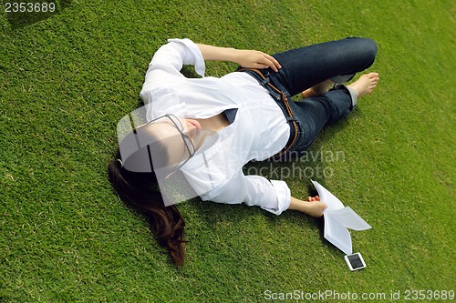 Image of Young woman reading a book in the park