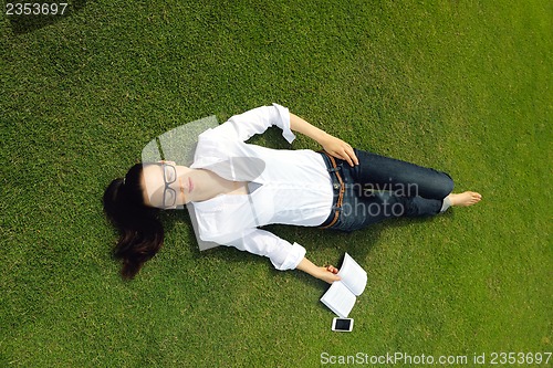 Image of Young woman reading a book in the park