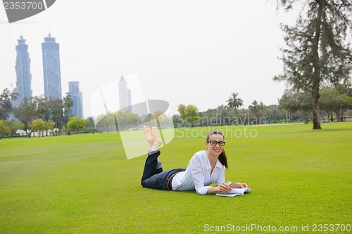 Image of Young woman reading a book in the park