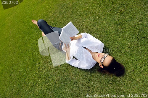 Image of Young woman reading a book in the park