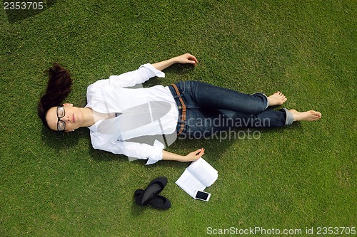 Image of Young woman reading a book in the park