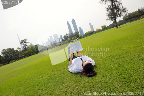 Image of Young woman reading a book in the park