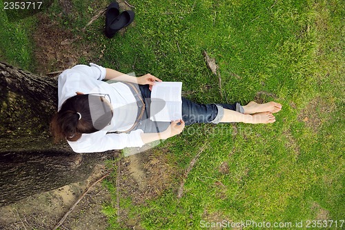 Image of Young woman reading a book in the park