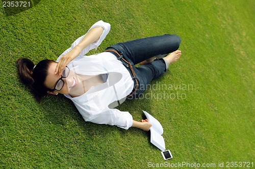 Image of Young woman reading a book in the park