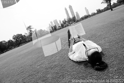 Image of Young woman reading a book in the park