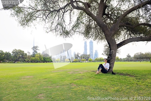 Image of Young woman reading a book in the park