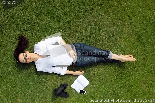 Image of Young woman reading a book in the park