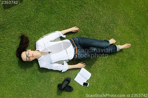 Image of Young woman reading a book in the park