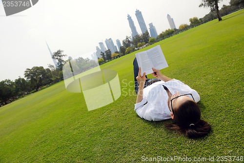 Image of Young woman reading a book in the park