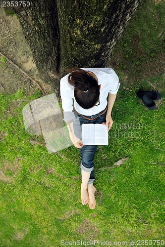 Image of Young woman reading a book in the park