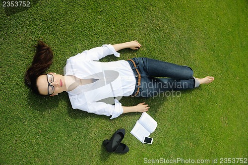 Image of Young woman reading a book in the park