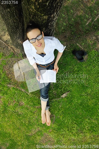 Image of Young woman reading a book in the park