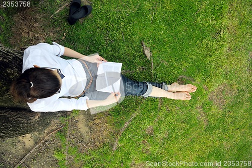 Image of Young woman reading a book in the park