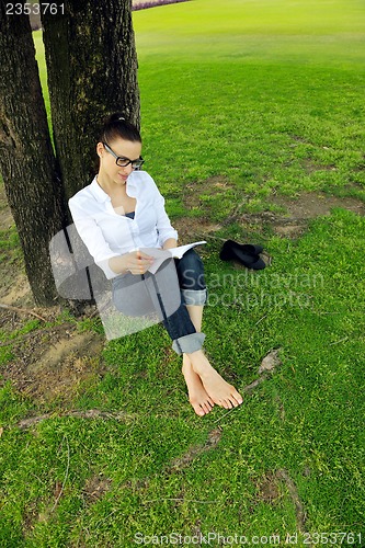 Image of Young woman reading a book in the park