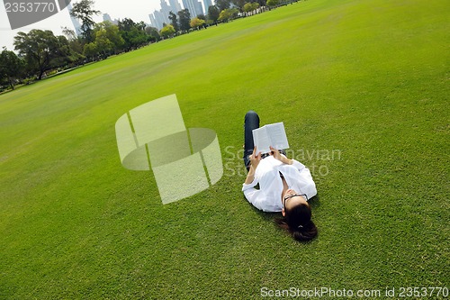 Image of Young woman reading a book in the park