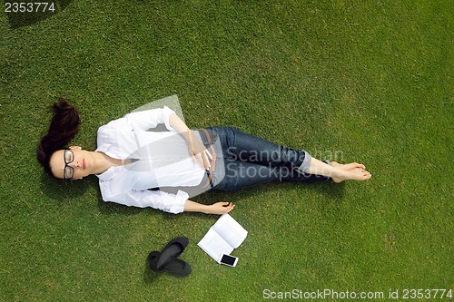 Image of Young woman reading a book in the park