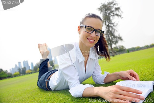 Image of Young woman reading a book in the park