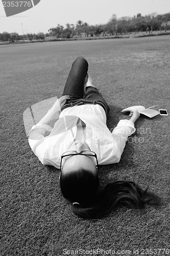 Image of Young woman reading a book in the park