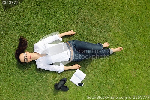 Image of Young woman reading a book in the park