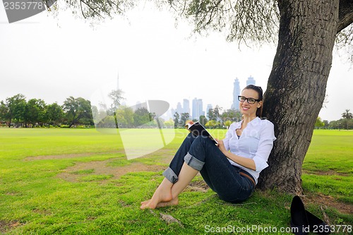Image of Young woman reading a book in the park