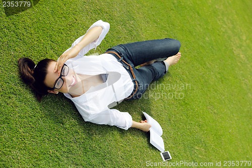 Image of Young woman reading a book in the park