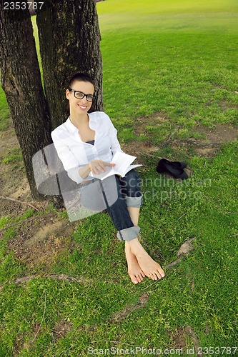Image of Young woman reading a book in the park