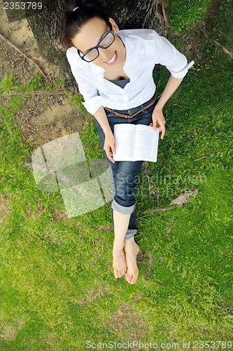 Image of Young woman reading a book in the park