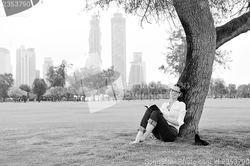 Image of Young woman reading a book in the park