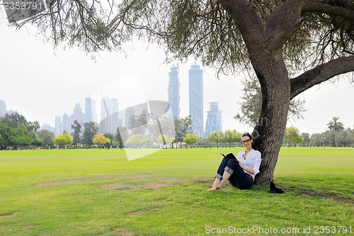 Image of Young woman reading a book in the park