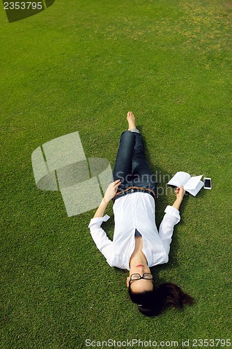 Image of Young woman reading a book in the park
