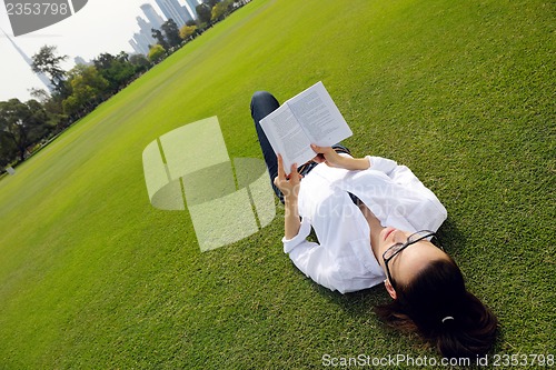 Image of Young woman reading a book in the park