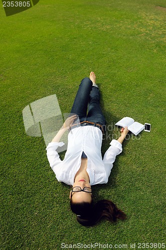 Image of Young woman reading a book in the park