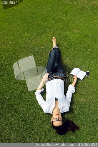 Image of Young woman reading a book in the park