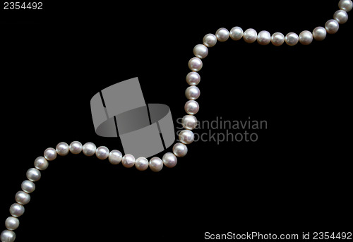 Image of White pearls on the black silk as background 