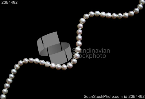 Image of White pearls on the black silk as background 