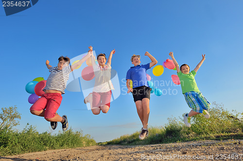 Image of happy children jumping on field with balloons