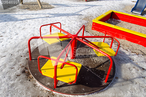 Image of carousel with yellow chairs and red rails winter 