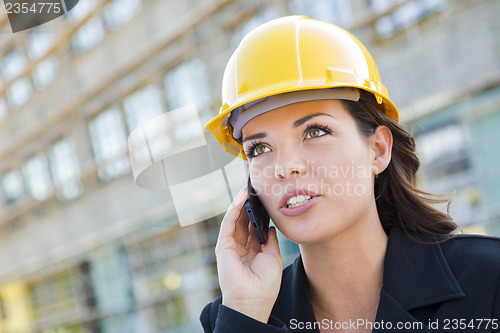 Image of Young Female Contractor Wearing Hard Hat on Site Using Phone