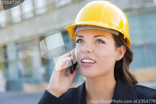 Image of Young Female Contractor Wearing Hard Hat on Site Using Phone