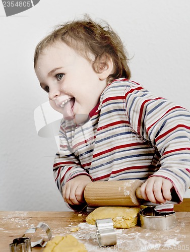 Image of happy young child with rolling pin in grey background