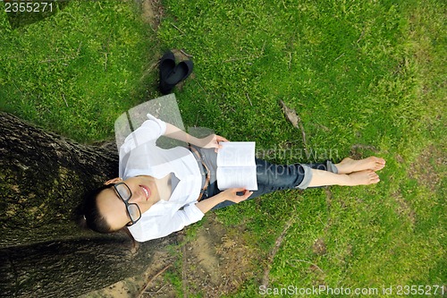 Image of Young woman reading a book in the park