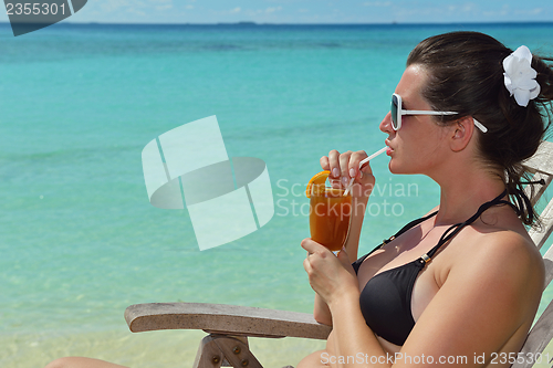 Image of Beautiful young woman with a drink by the sea