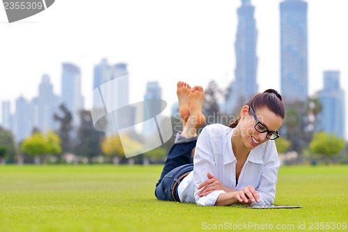 Image of Beautiful young woman with  tablet in park