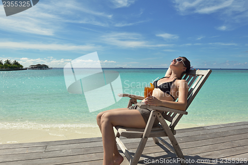 Image of Beautiful young woman with a drink by the sea