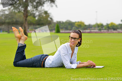 Image of Beautiful young woman with  tablet in park