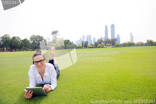 Image of Beautiful young woman with  tablet in park